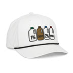 A white baseball cap featuring a graphic of four milk bottles labeled 1% CHOCO, 2%, and WHOLE on the front panel, with a black braided trim across the brim and 'DON PANCHITO' embroidered on the side.