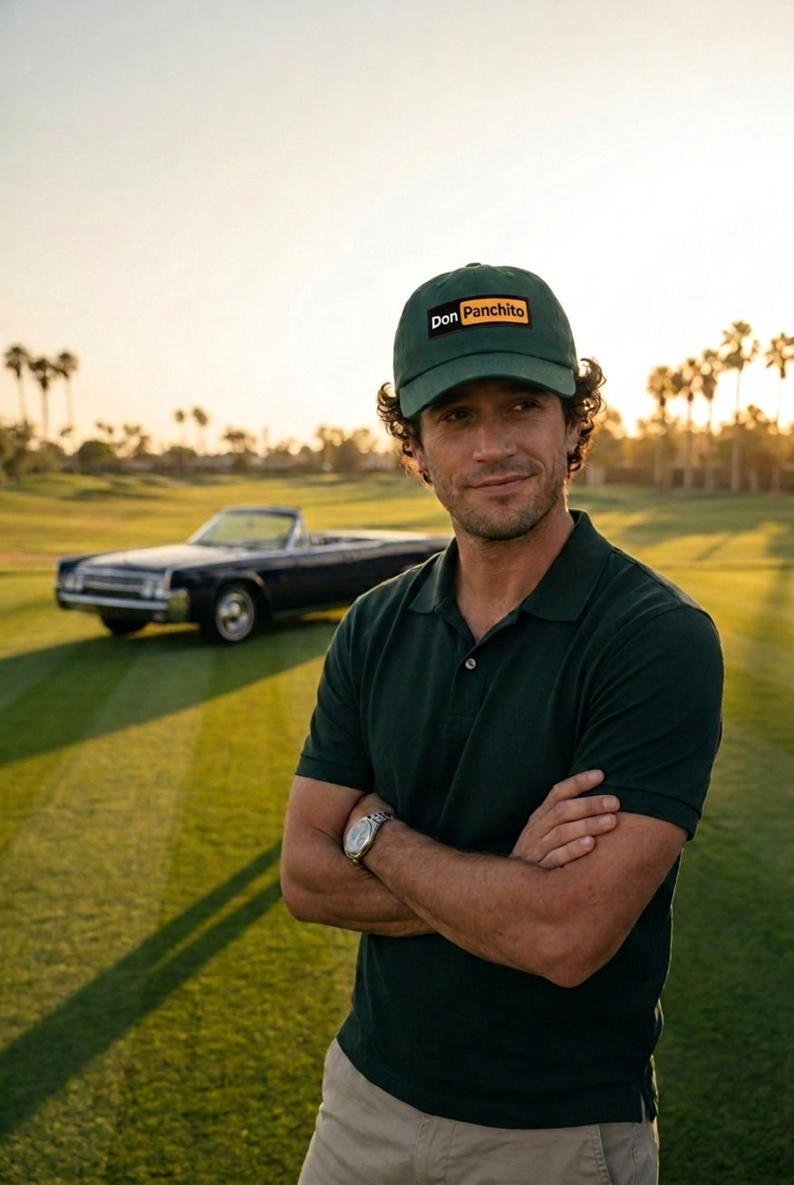 A man stands on a golf course at sunset wearing a dark green polo shirt, khaki pants, and the green DON PANCHITO LATENIGHT dad hat. A dark convertible car is parked in the background.