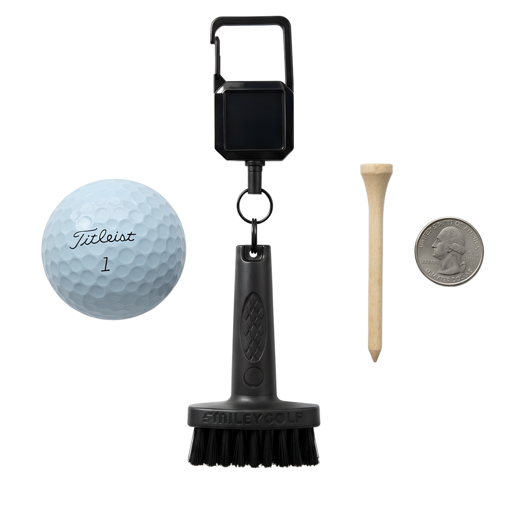 A golf club cleaning brush kit on a white background, including the SMILEY GOLF Mini Golf Brush with a Clip, a Titleist golf ball, a wooden tee, and a US quarter for scale.
